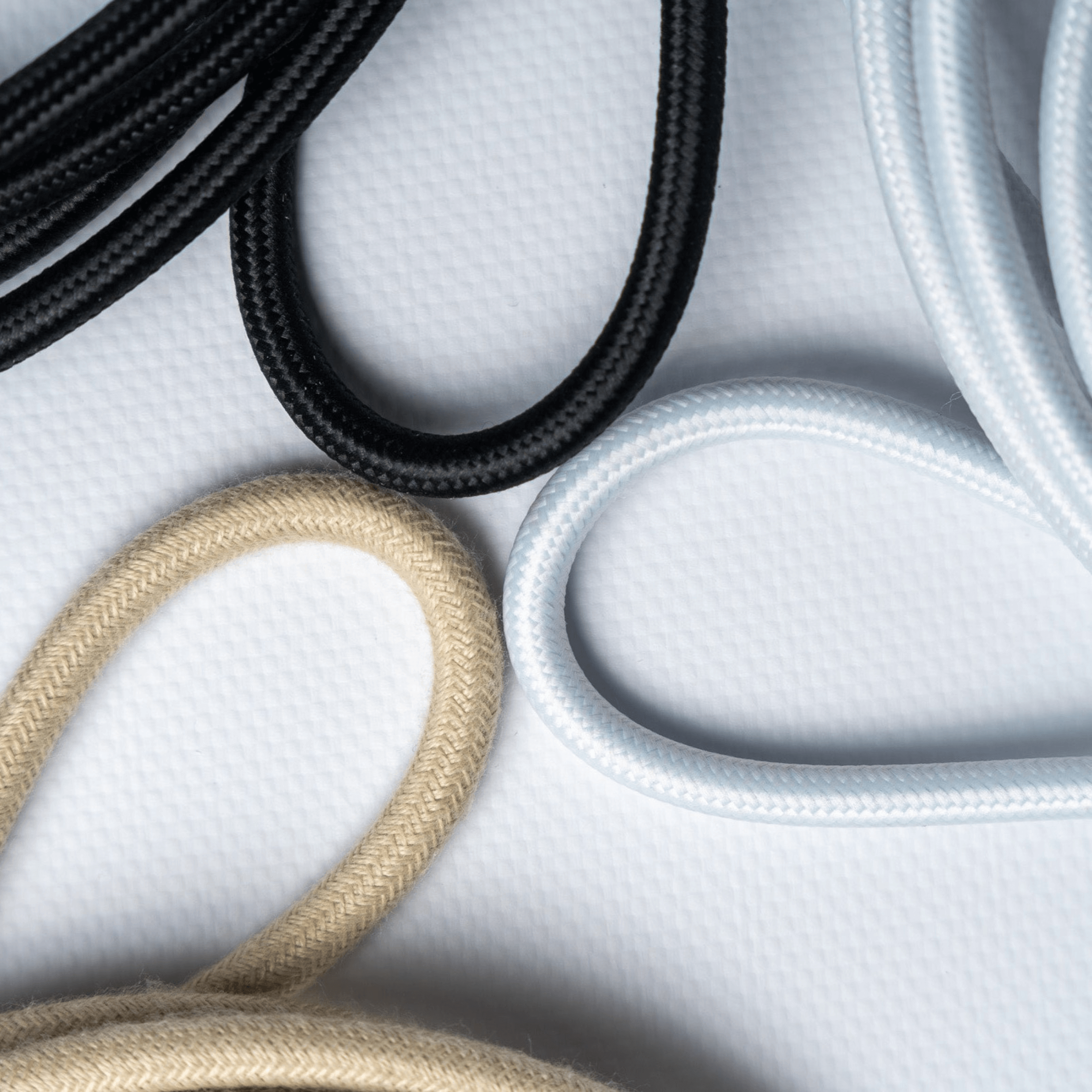Des cables cotons de couleur blanc, beige et noir sont présentés sur cette photo.