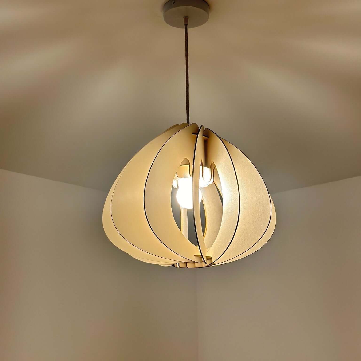 La photo montre un luminaire suspendue design en forme de pétales de carton bois, éclairée et fixée au plafond d’une pièce - Alba - Papa Ampère